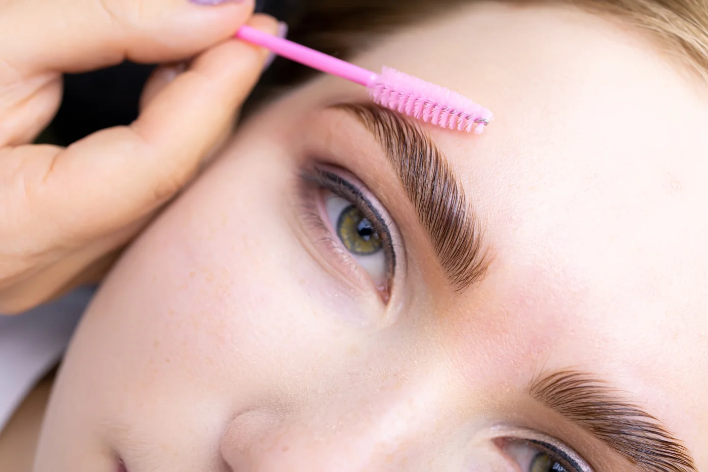 Brow hairs being carefully brushed during a treatment